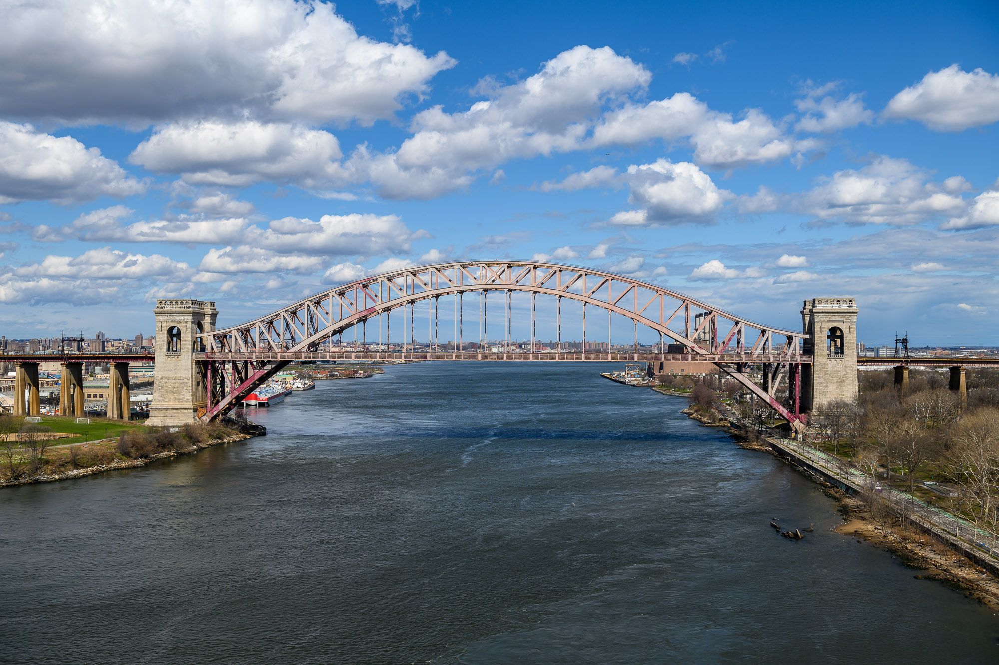 Hell Gate bridge on a day with blue skies and scattered clouds in April 2022.