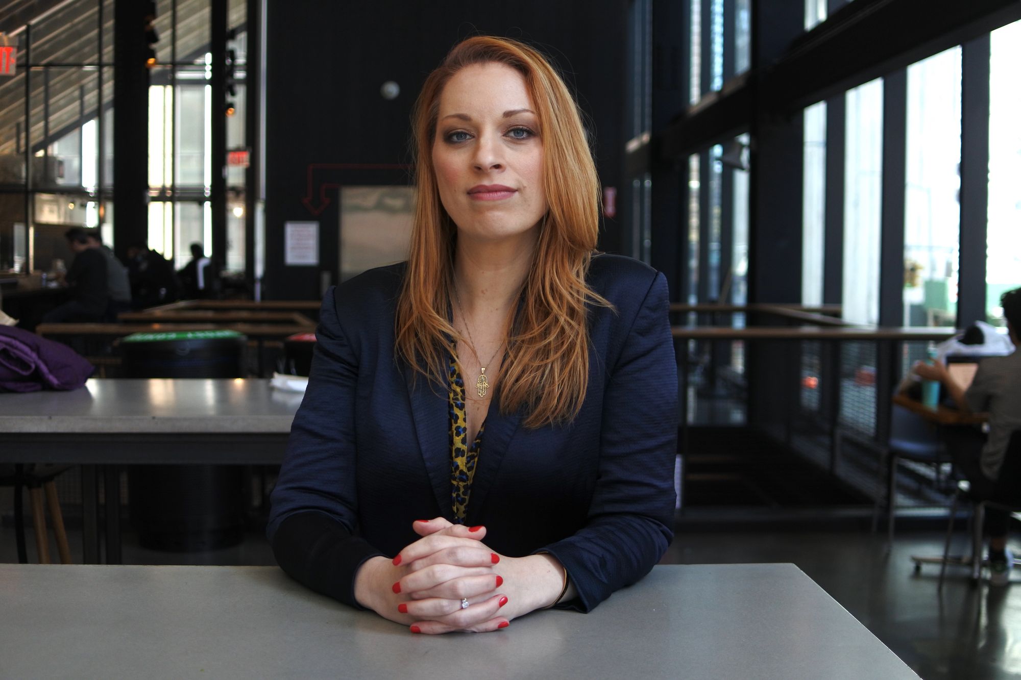 Former DOC Investigator Sarena Townsend poses for a photo sitting down in a blue blazer with her hands claspsed.