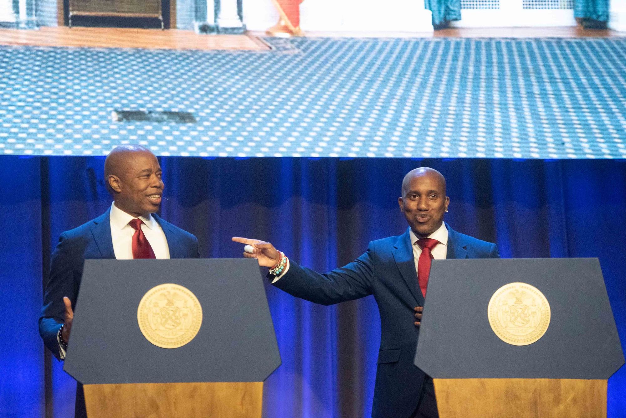Chris Redd and New York City Mayor Eric Adams standing behind podiums.