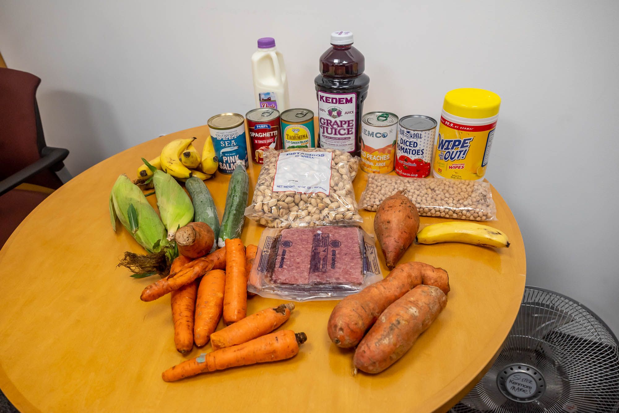 Carrots, corn, sweet potatoes, grape juice, and other items on a table.