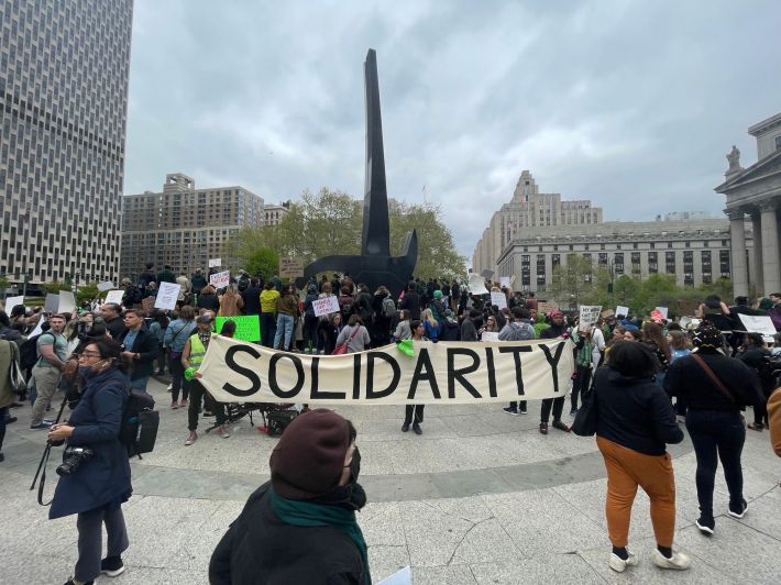 A crowd of people standing nearby a large sign that reads "SOLIDARITY."