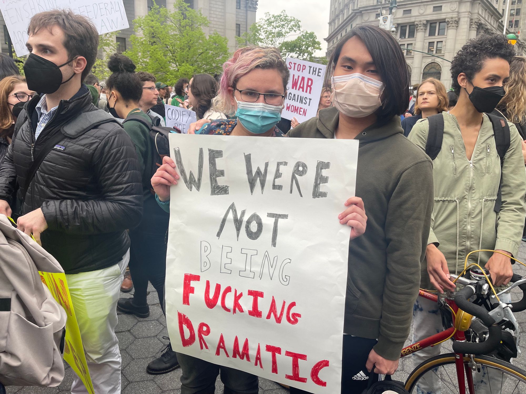 Two people holding a sign that says "We were not being fucking dramatic."