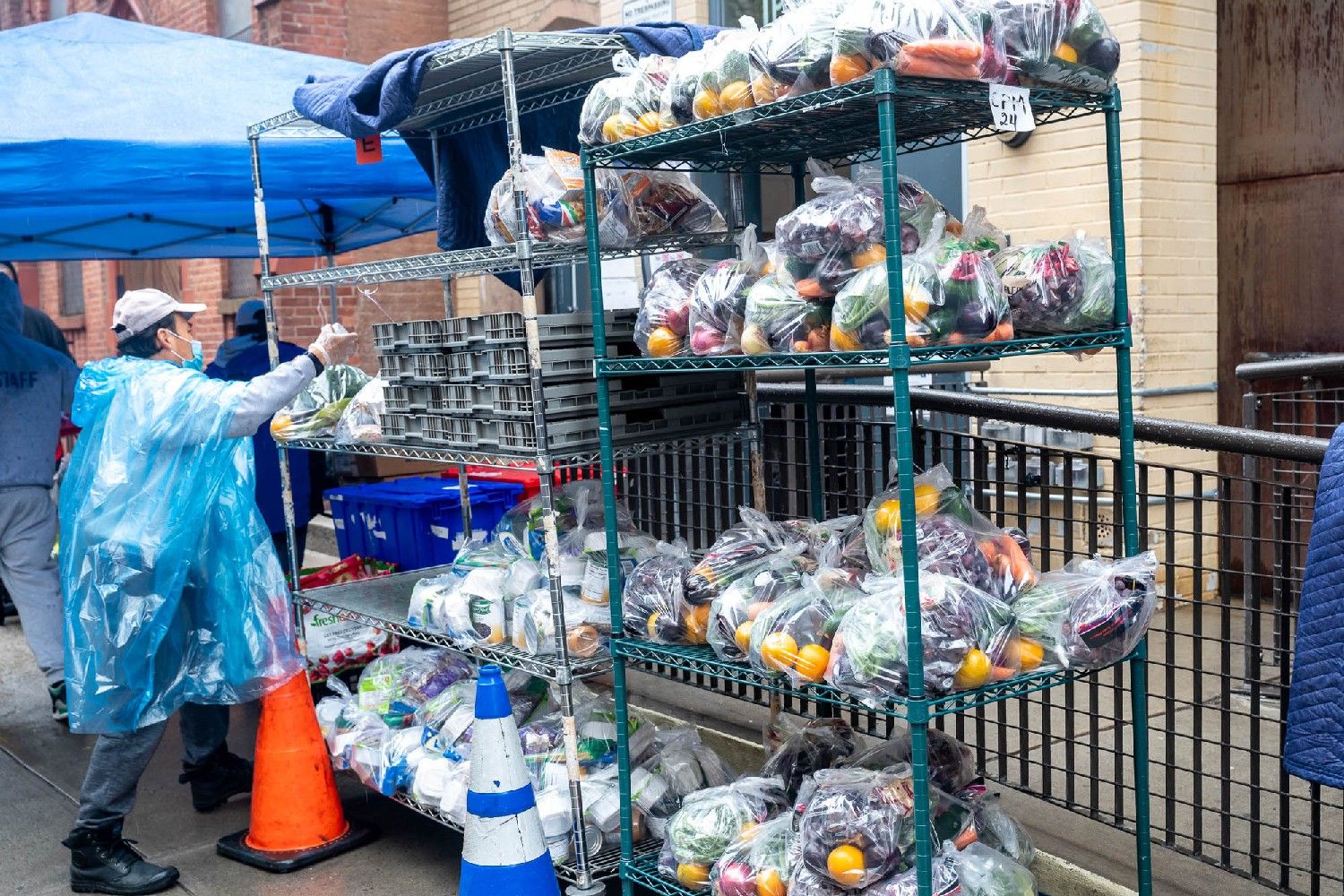 A man grabbing an item from metal shelving at an outdoor food distribution site with New York Common Pantry.