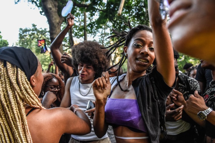 A woman wearing a purple crop top dances in a crowd of people.