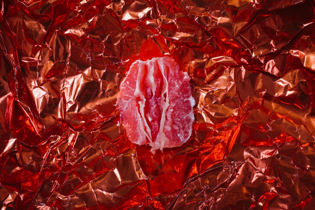 A section of a grapefruit resting atop shiny pink fabric
