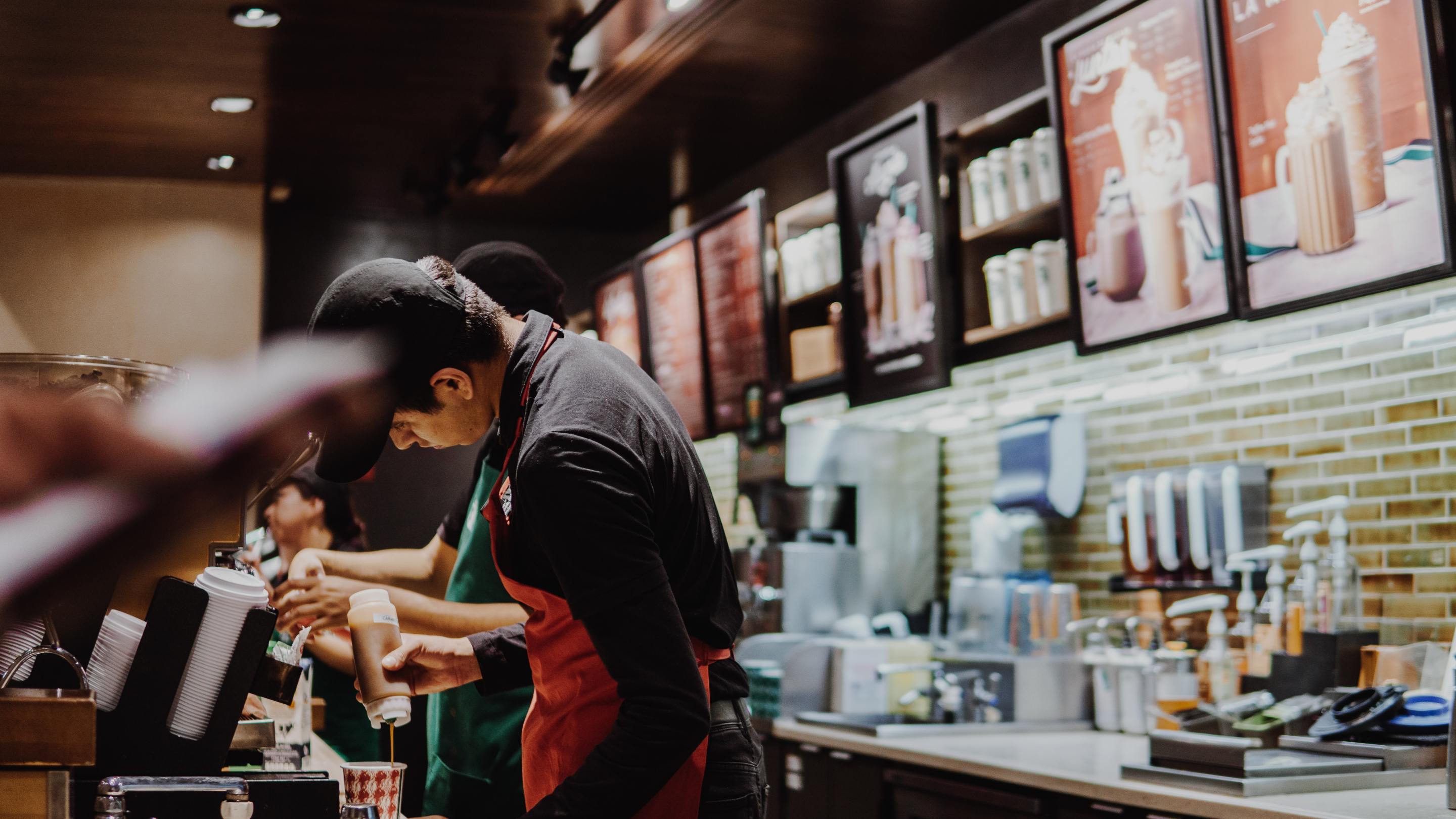 Two baristas work behind the counter at Starbucks