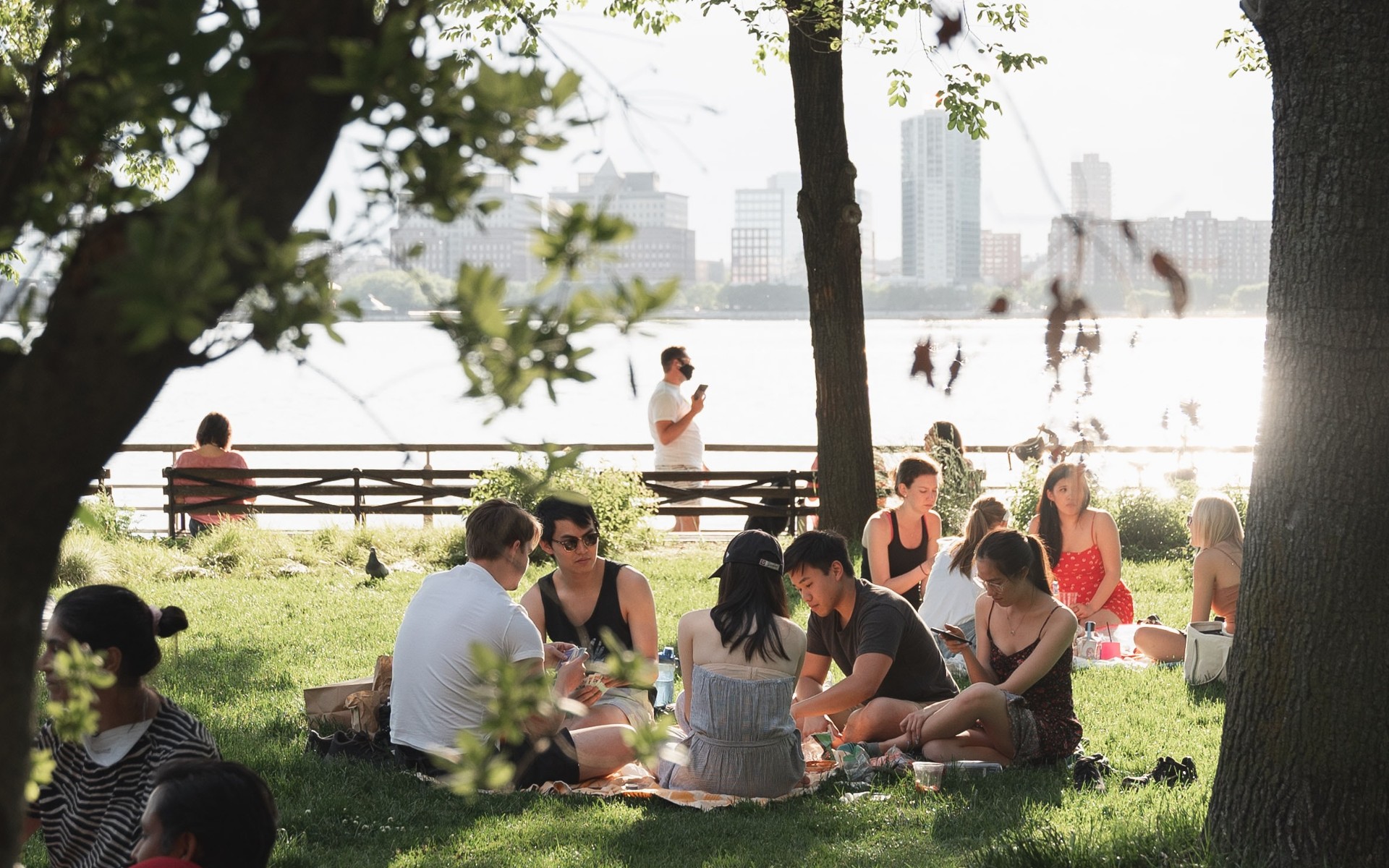 A group of people sitting together on a lawn by the Hudson River
