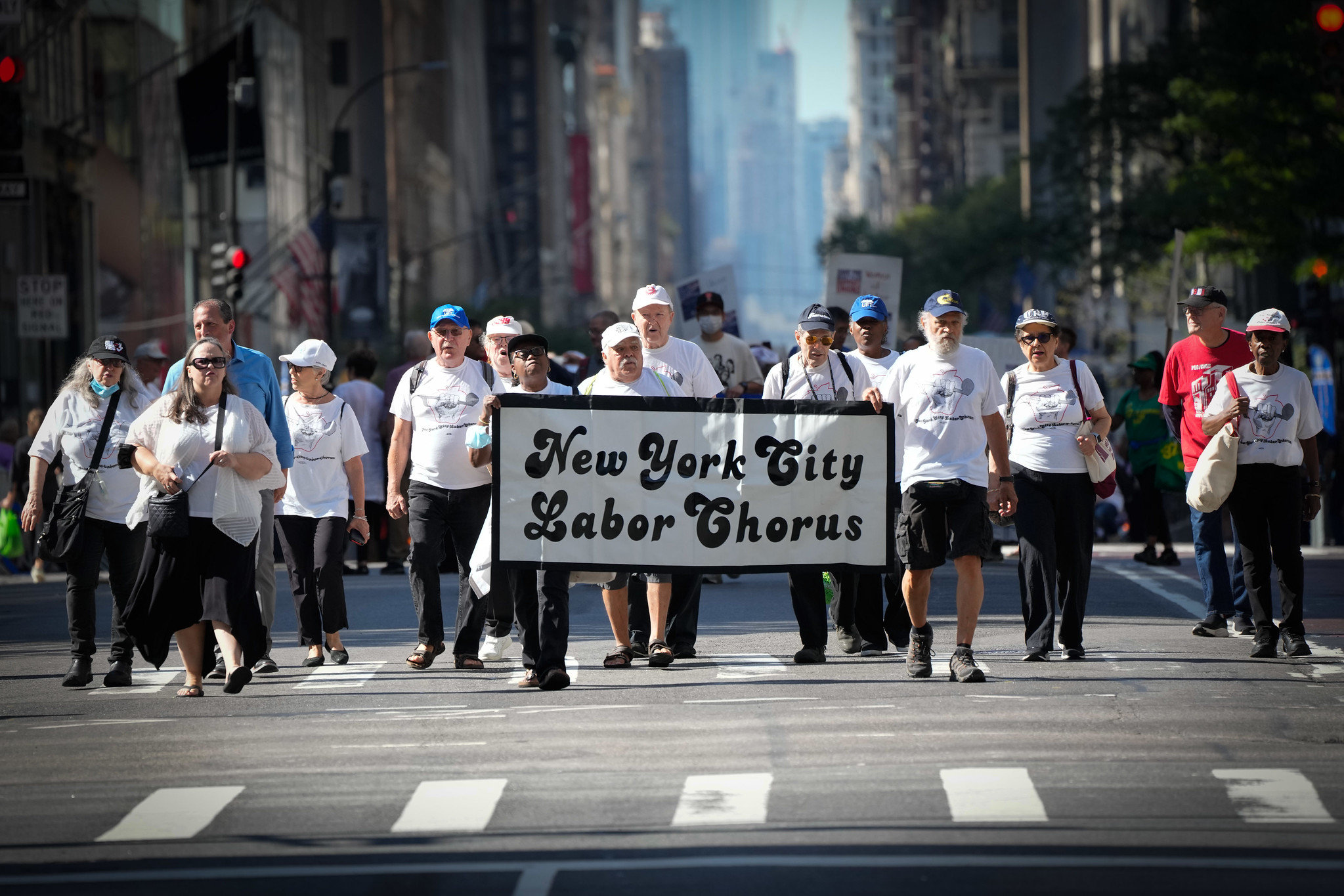A group of trade union labor members march in the Labor Day parade behind a banner that says "New York City Labor Chorus"