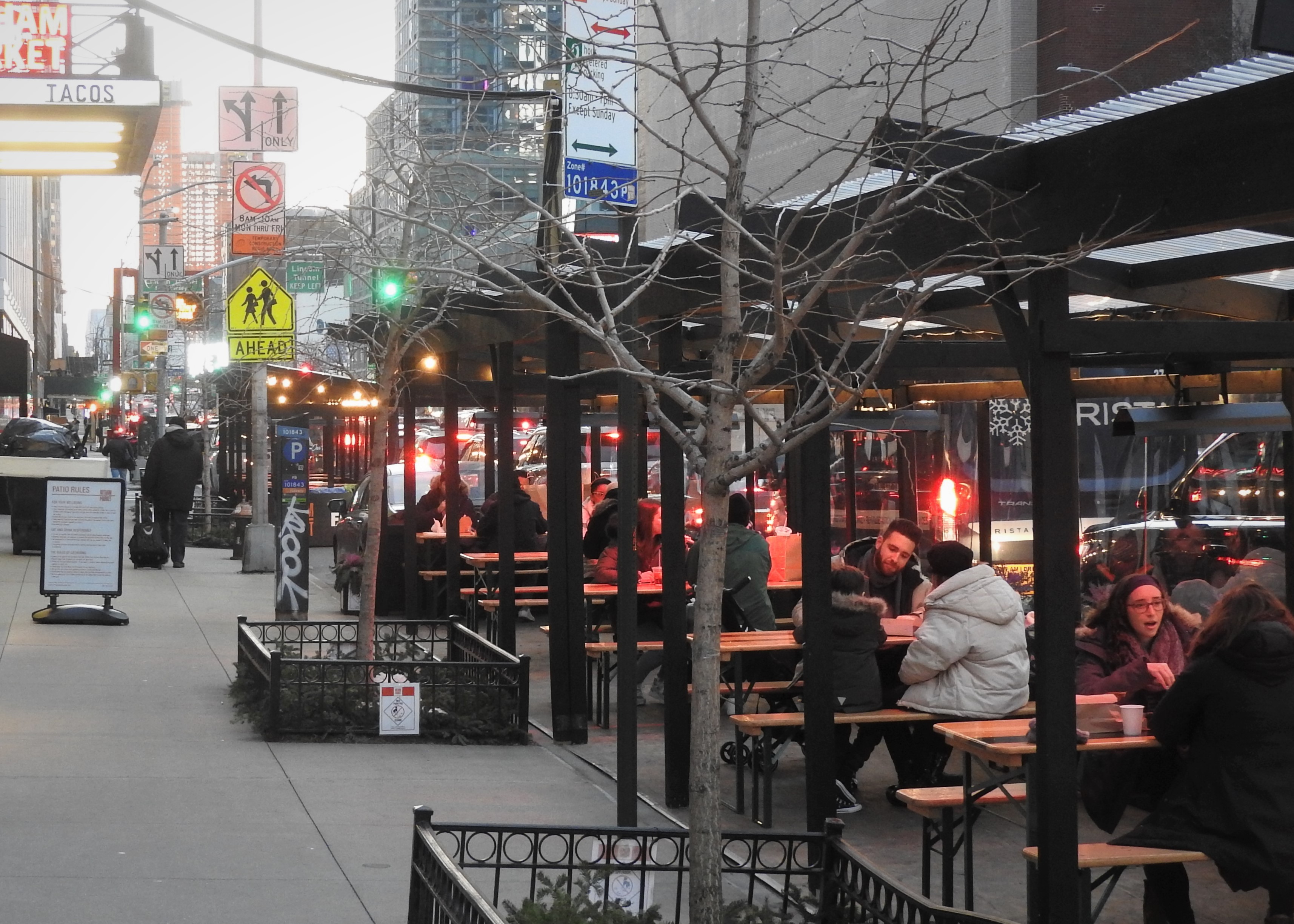 People sit outside in dining sheds where parking spaces used to be.