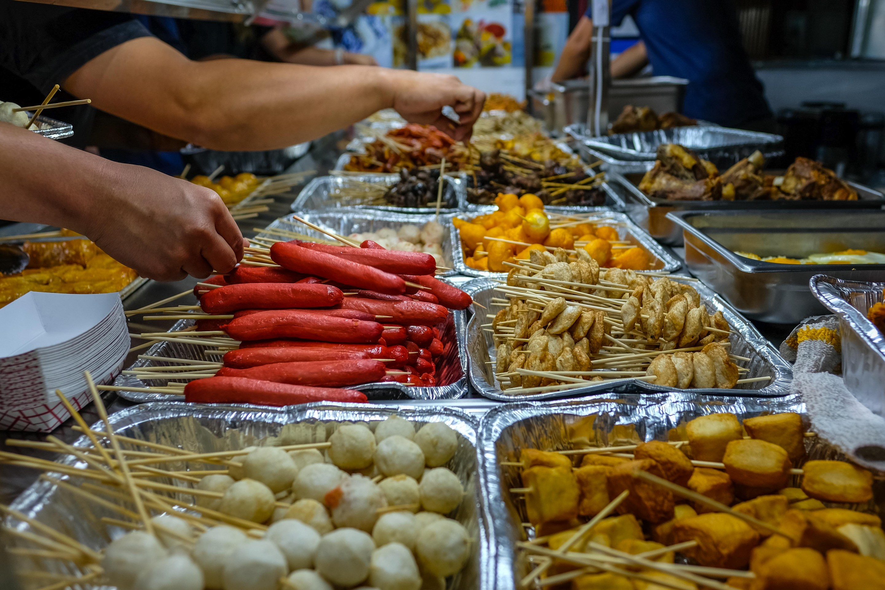Numerous trays of skewers of all shapes and sizes sit in aluminum trays, waiting for people to take them.