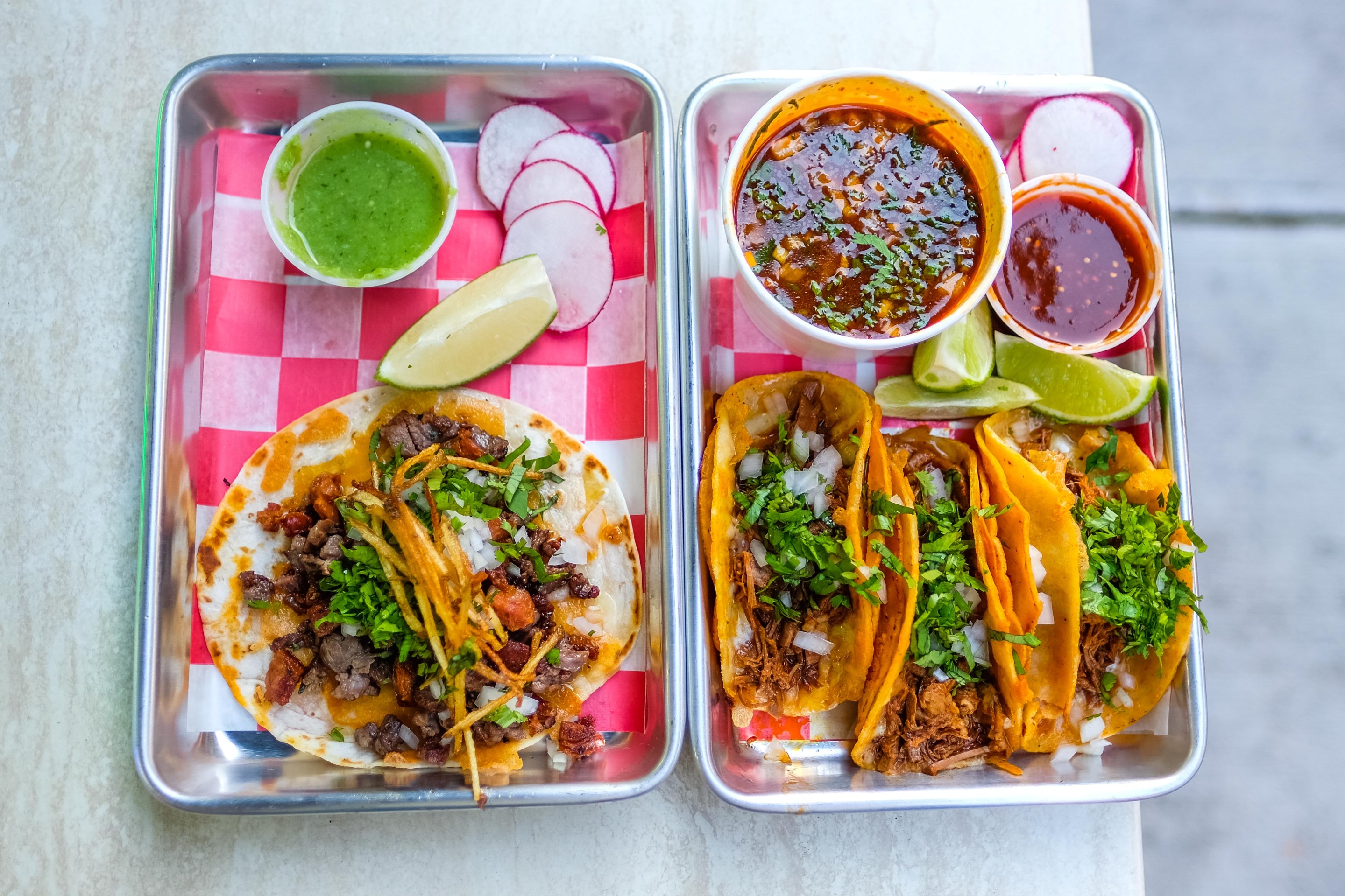 Delicious birria tacos in little steel trays.