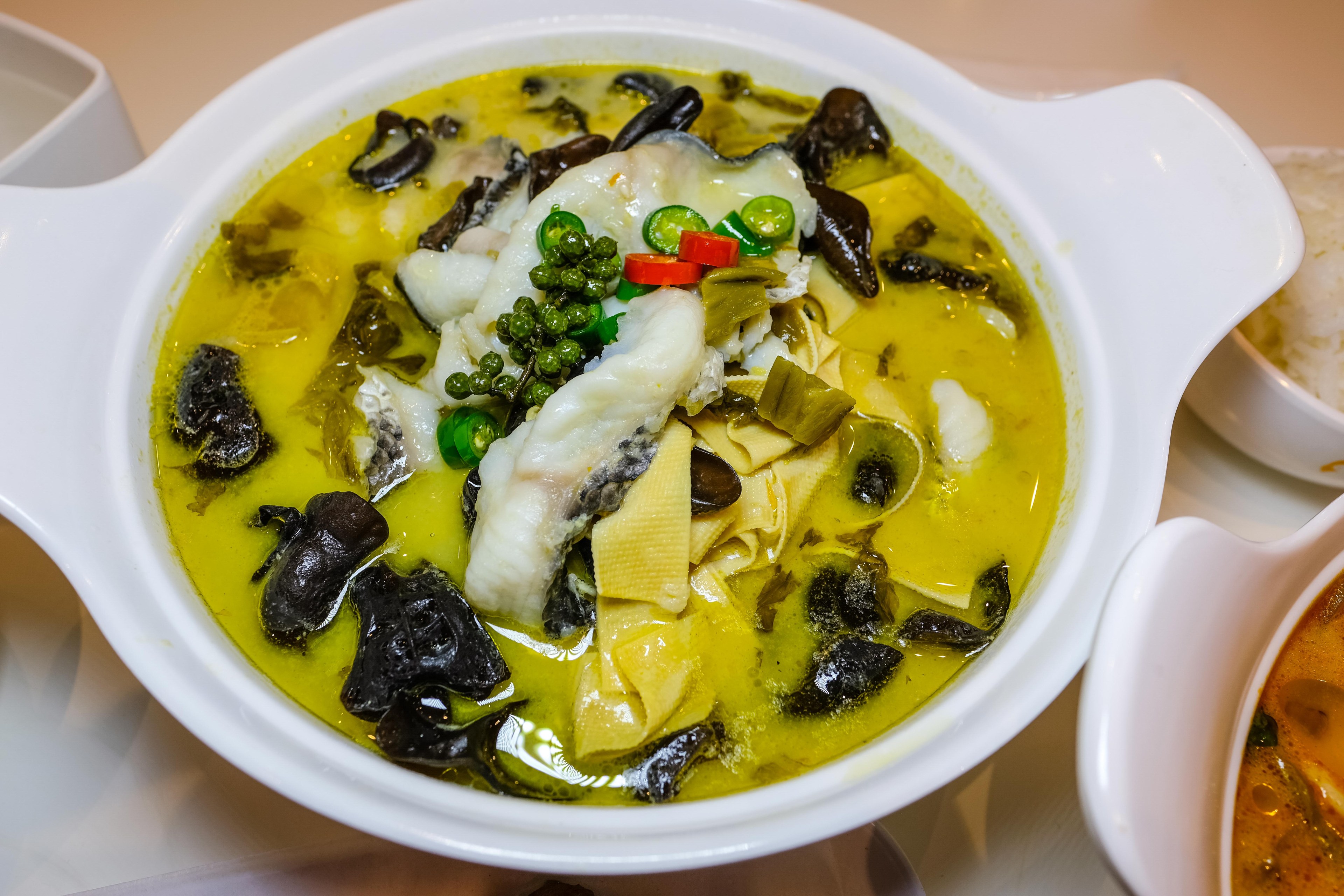 A bowl of Pickled mustard snakehead fish with green peppercorn, black fungus, and bean curd.