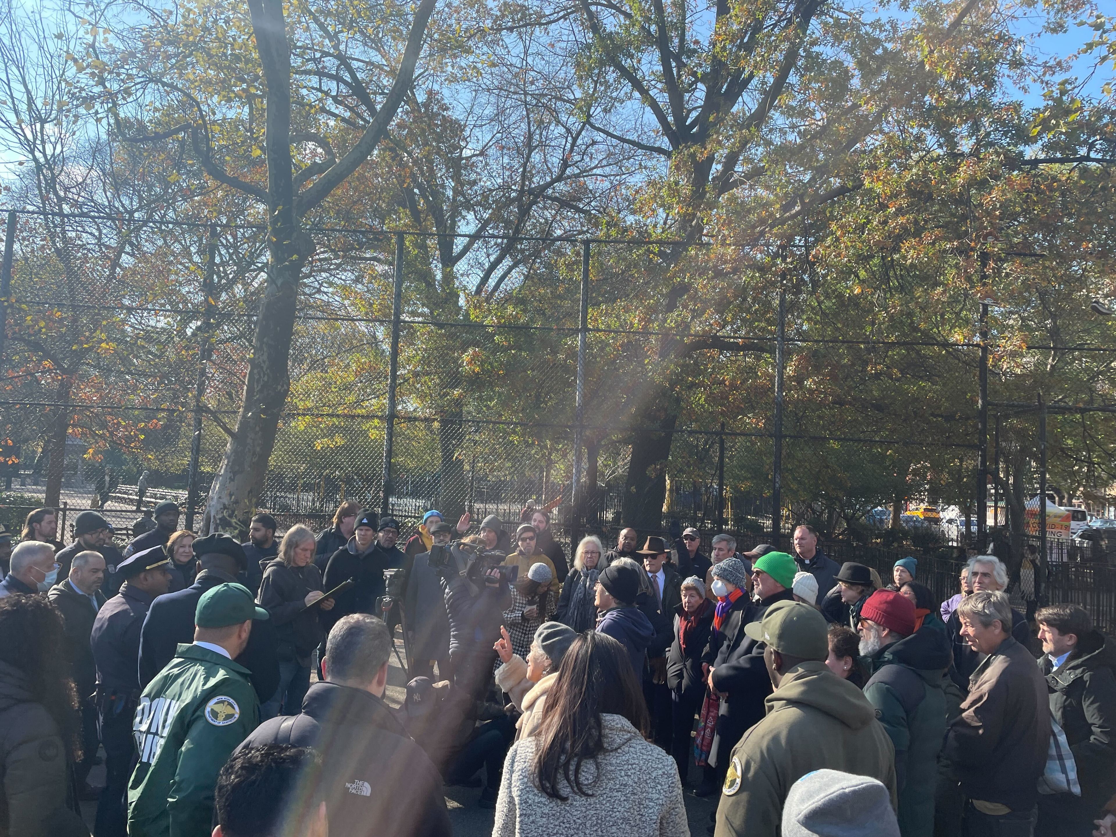A crowd of around three dozen people gather on a cold sunny morning in Tompkins square park to discuss public safety.