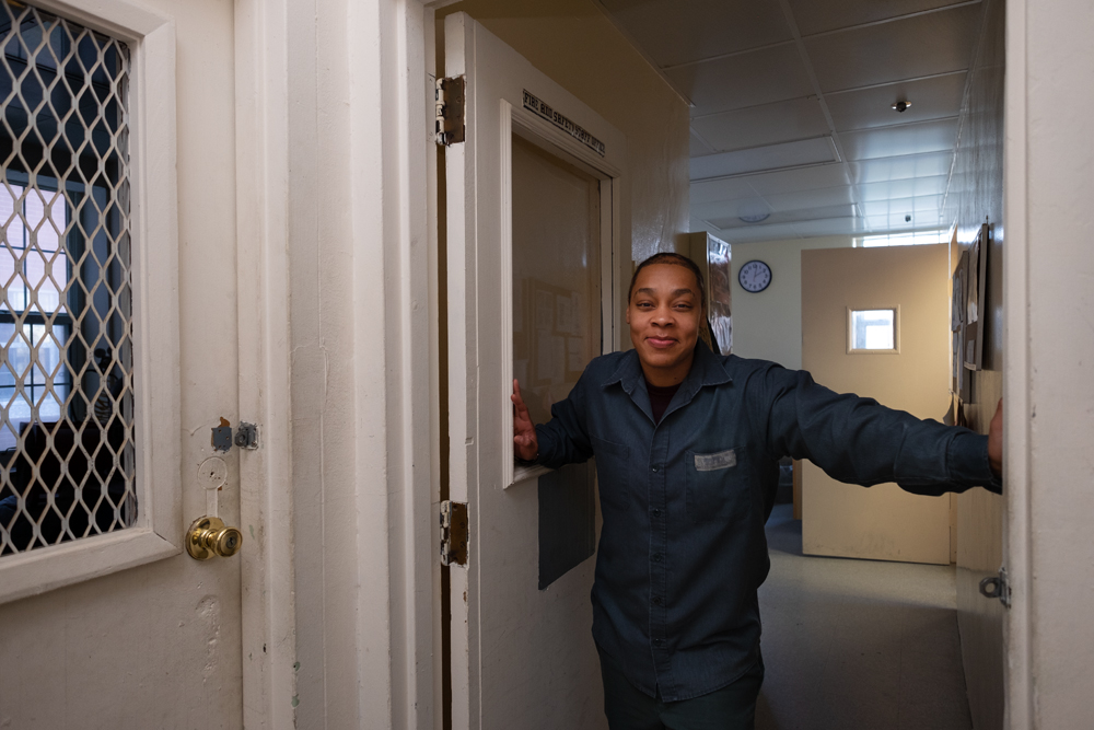 Taliyah Taylor standing in a doorway wearing blue coveralls in the Bedford Hills Correctional Facility, 2018