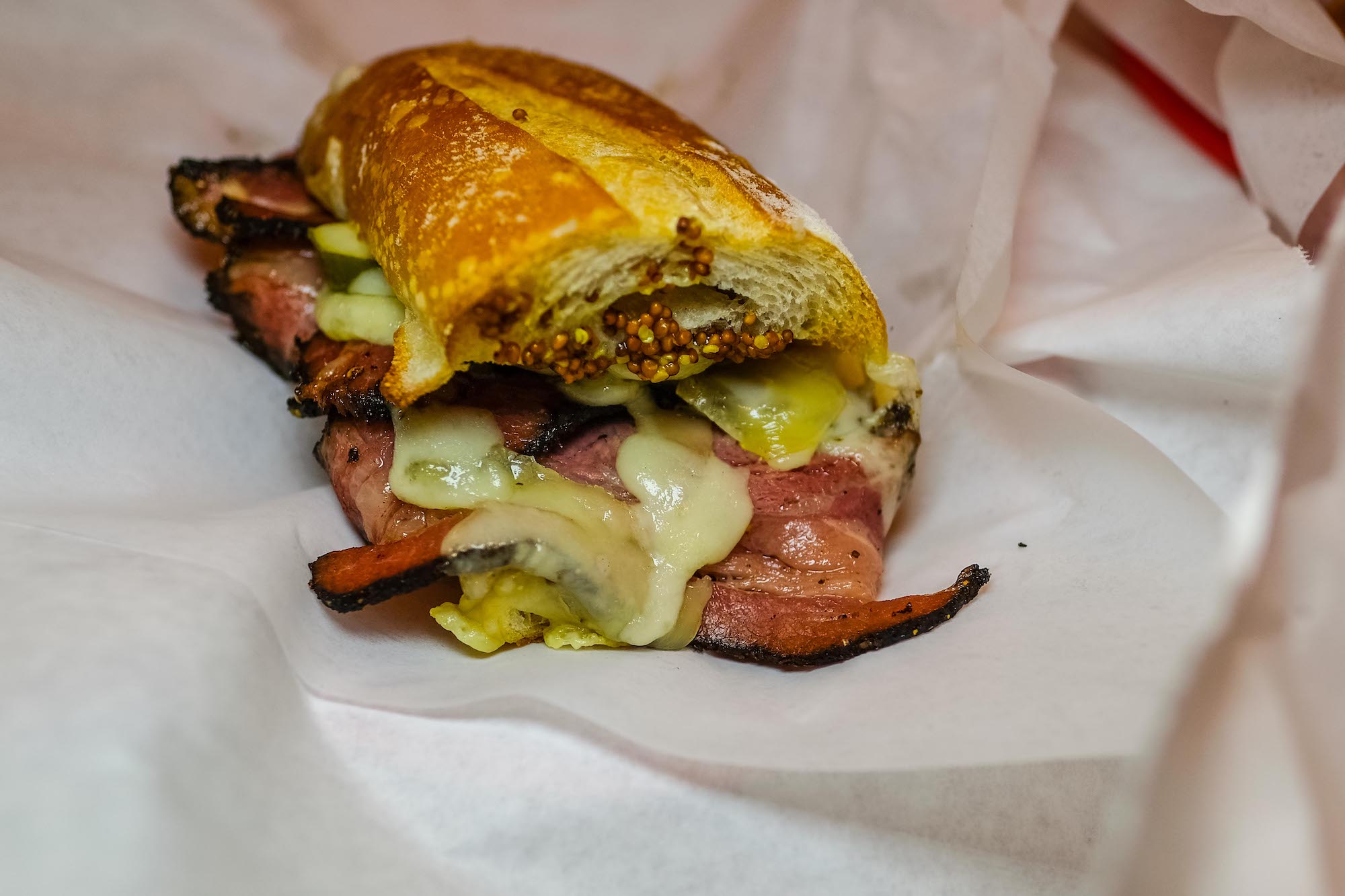 Half a pastrami 'n Swiss melt, on a white piece of butcher paper.