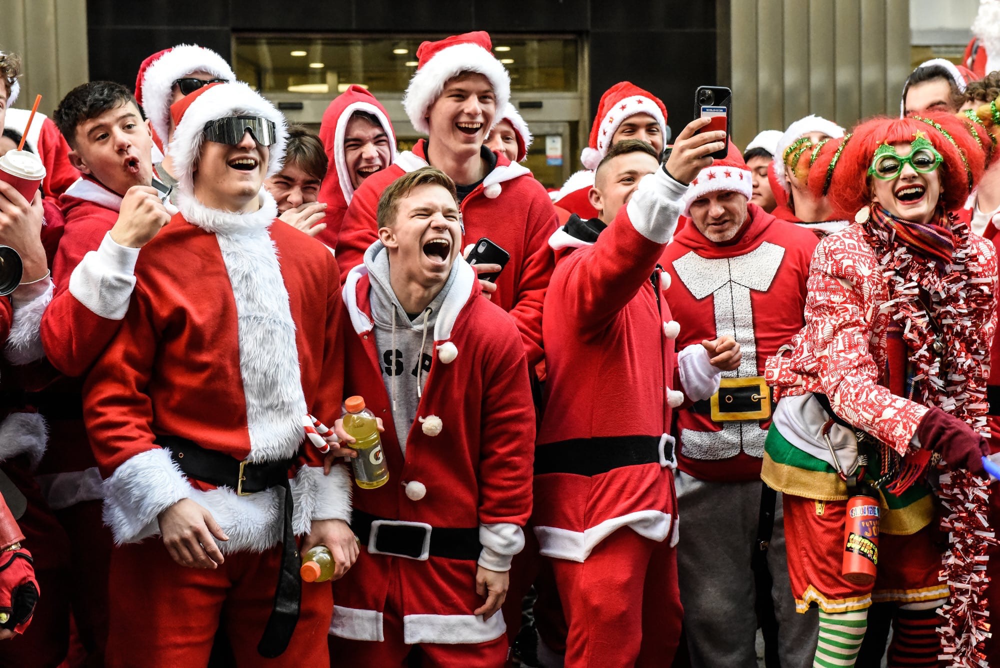A group of revelers at SantaCon laugh at something on the street.