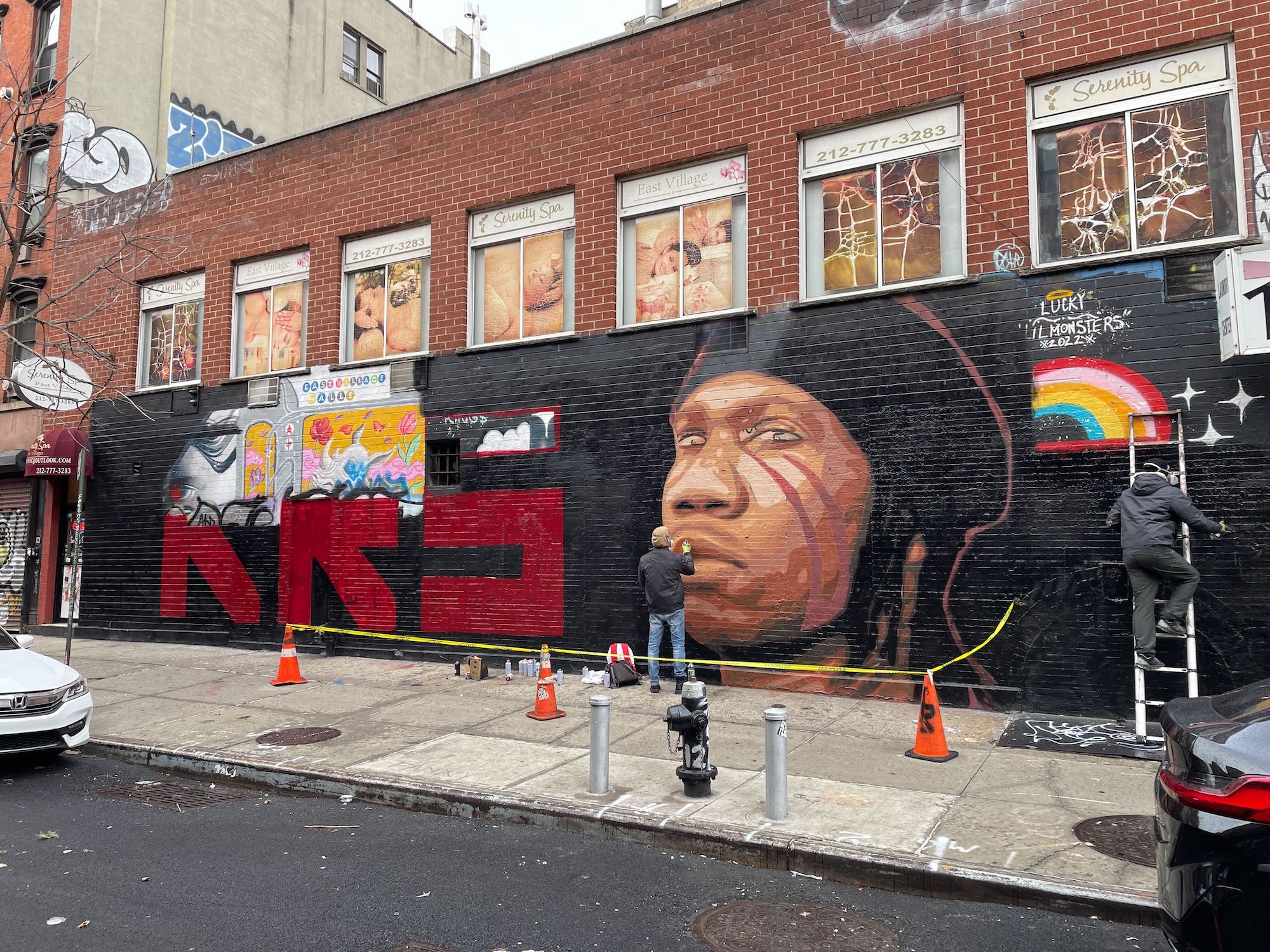 Two people paint a mural of KRS One.