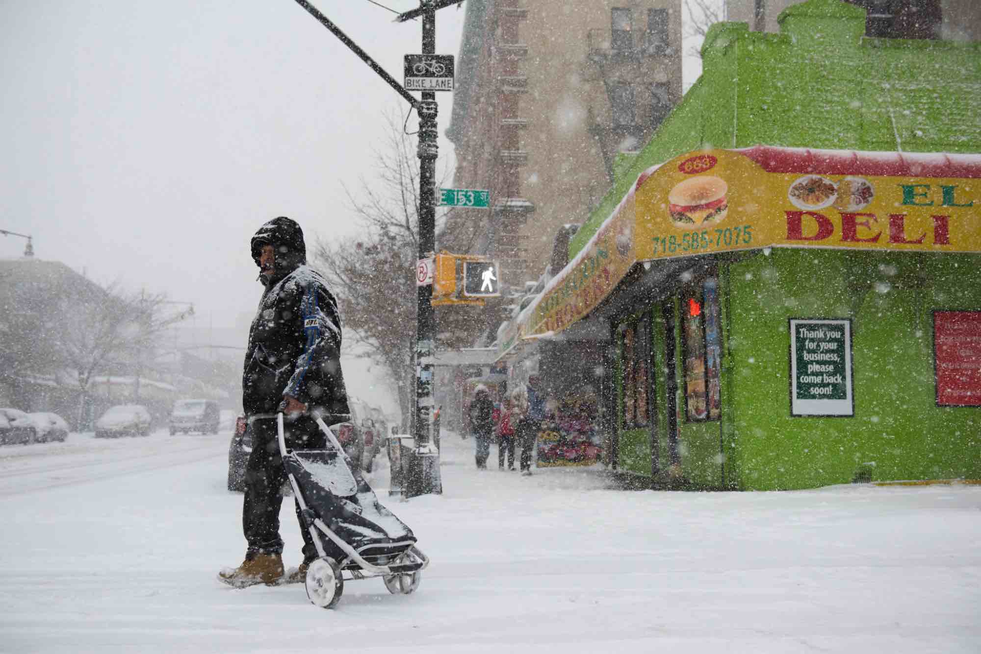 A man pulls a cart in the snow.