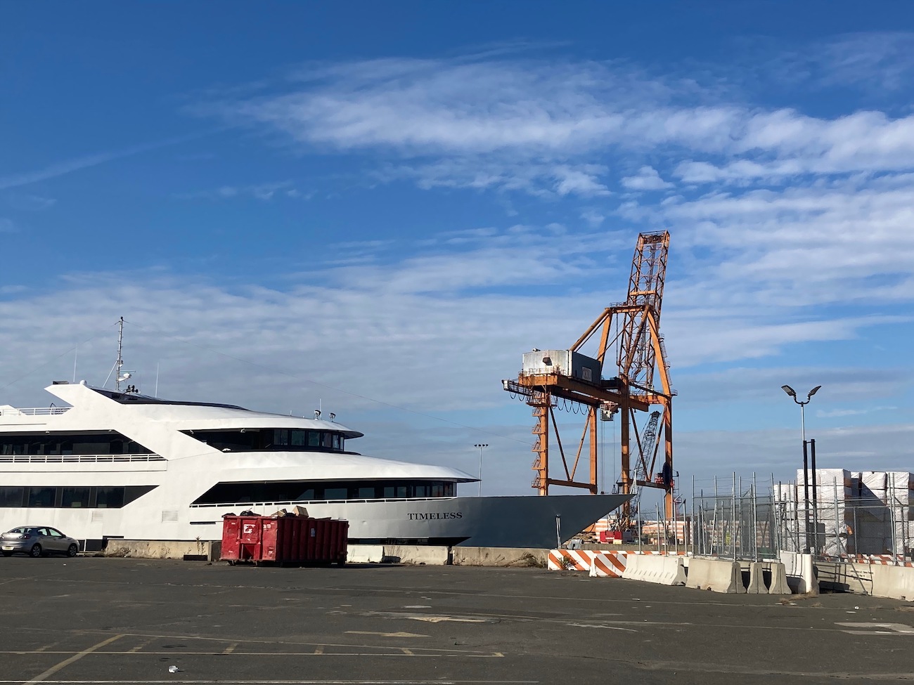 A large beat up yacht named "Timeless" sits next to a shipping container remover in Red Hook.