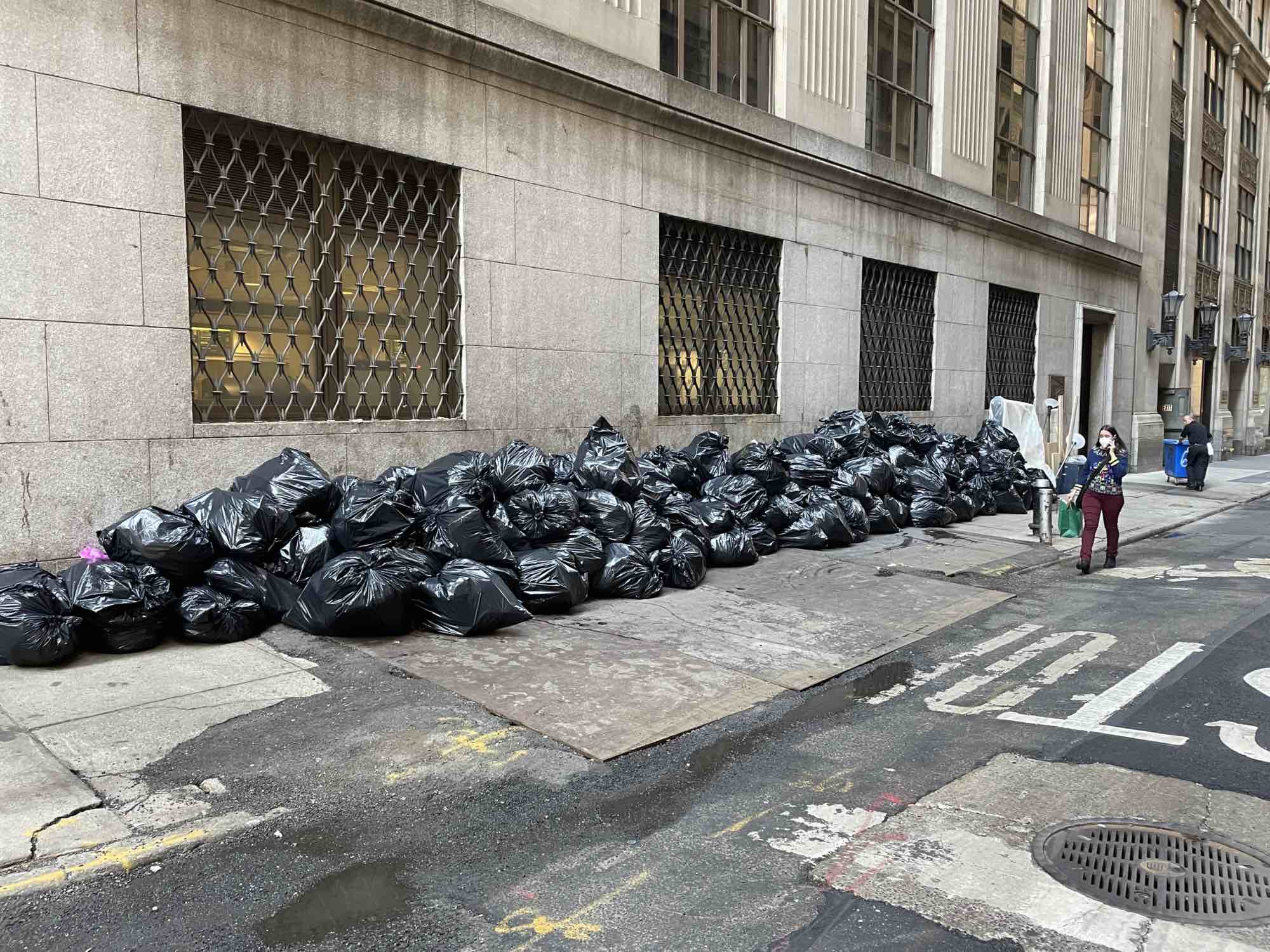 A huge line of black trash bags gobbles up a sidewalk in FiDi.