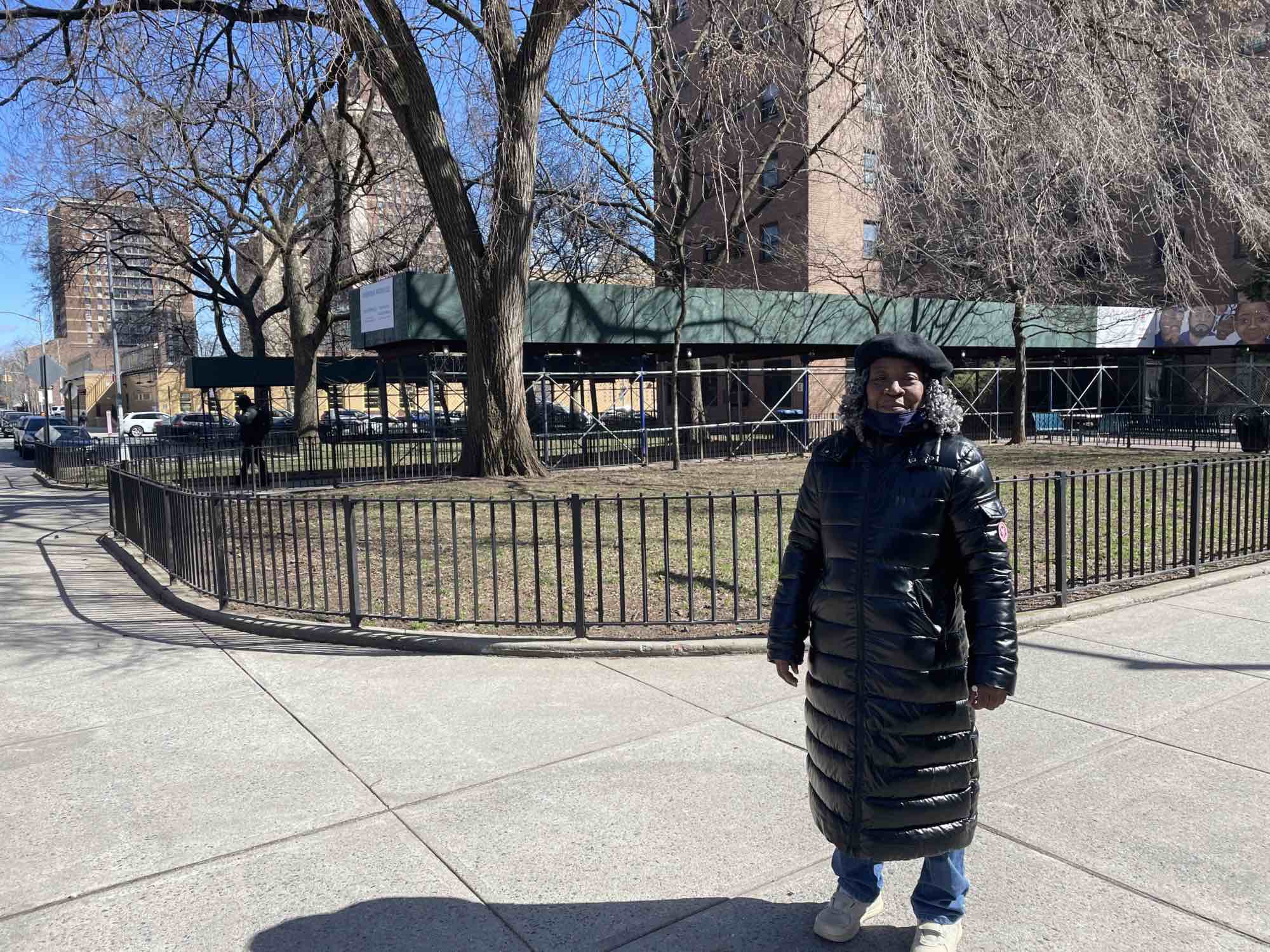 Naomi Johnson poses in front of the scaffolding that has stood at the Howard Houses for more than 6 years.