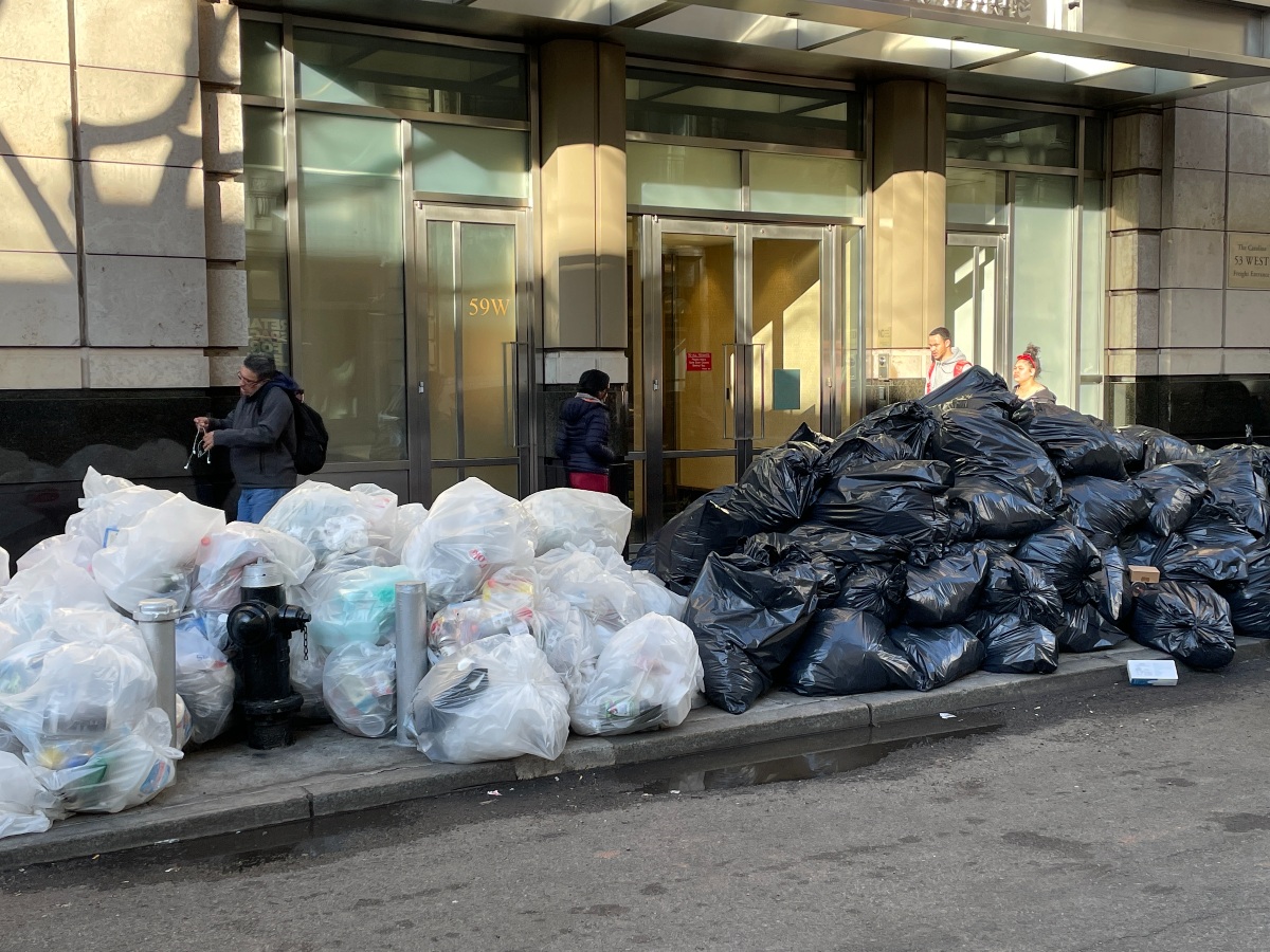 Trash and recycling bags line a sidewalk.