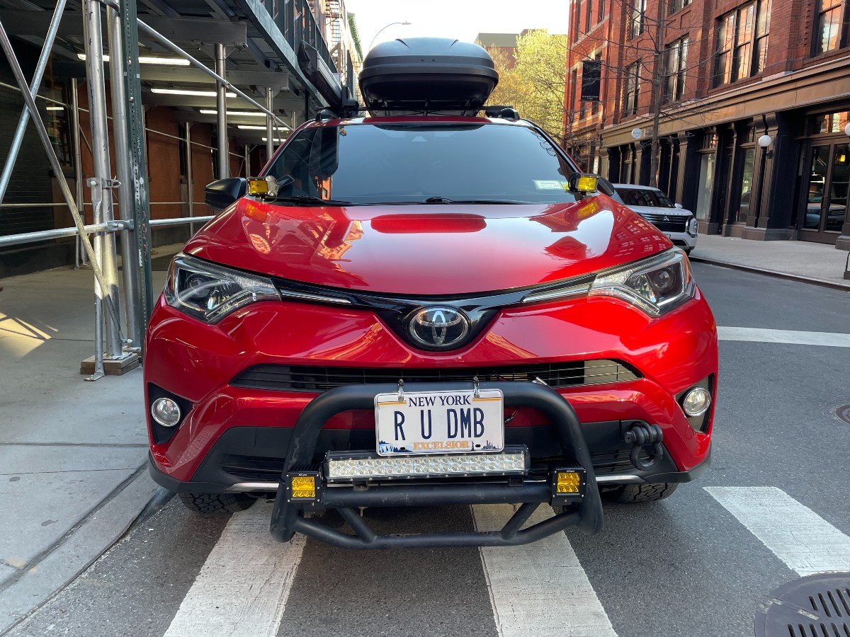 A red car with a cheeky vanity plate that says "R U DMB" as in "Are you dumb?"