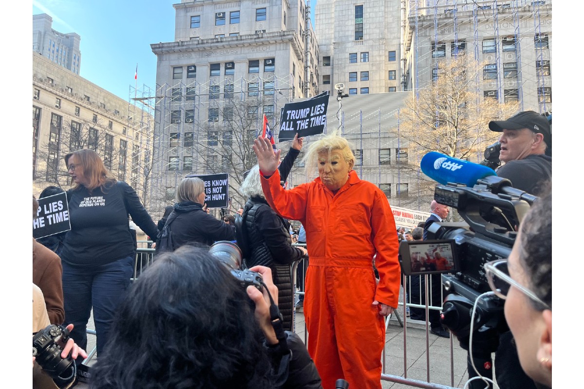 Someone in an orange jumpsuit and a Donald Trump mask demonstrating outside of the Manhattan Criminal Courthouse on the day of Donald Trump's arraignment.