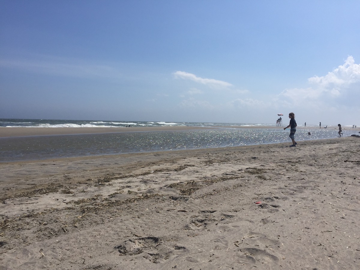A sandy stretch of Rockaway Beach on a sunny day.