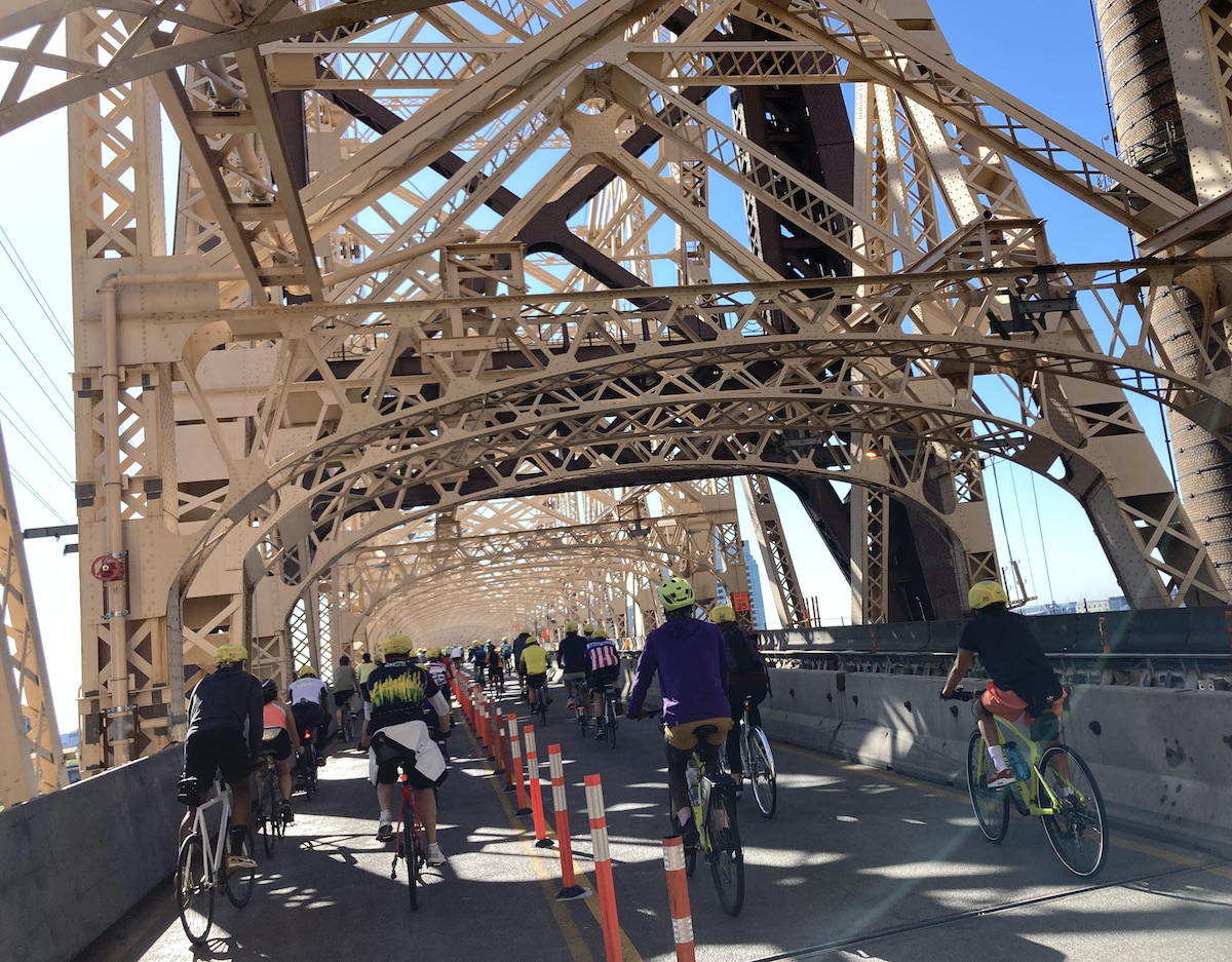 A group of cyclists riding on the Queensboro Bridge.