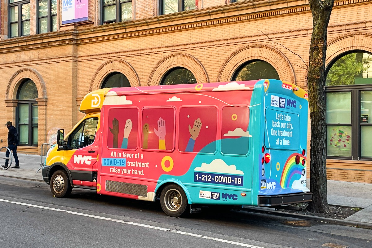 A brightly colored NYC COVID-19 testing van parked on a city street.
