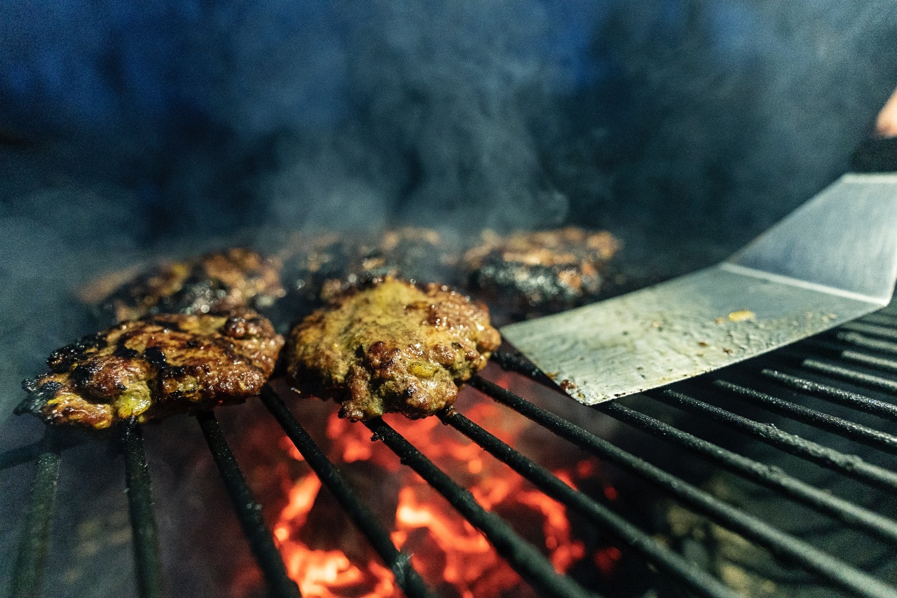 A close-up of a bunch of hamburger patties on a charcoal grill.