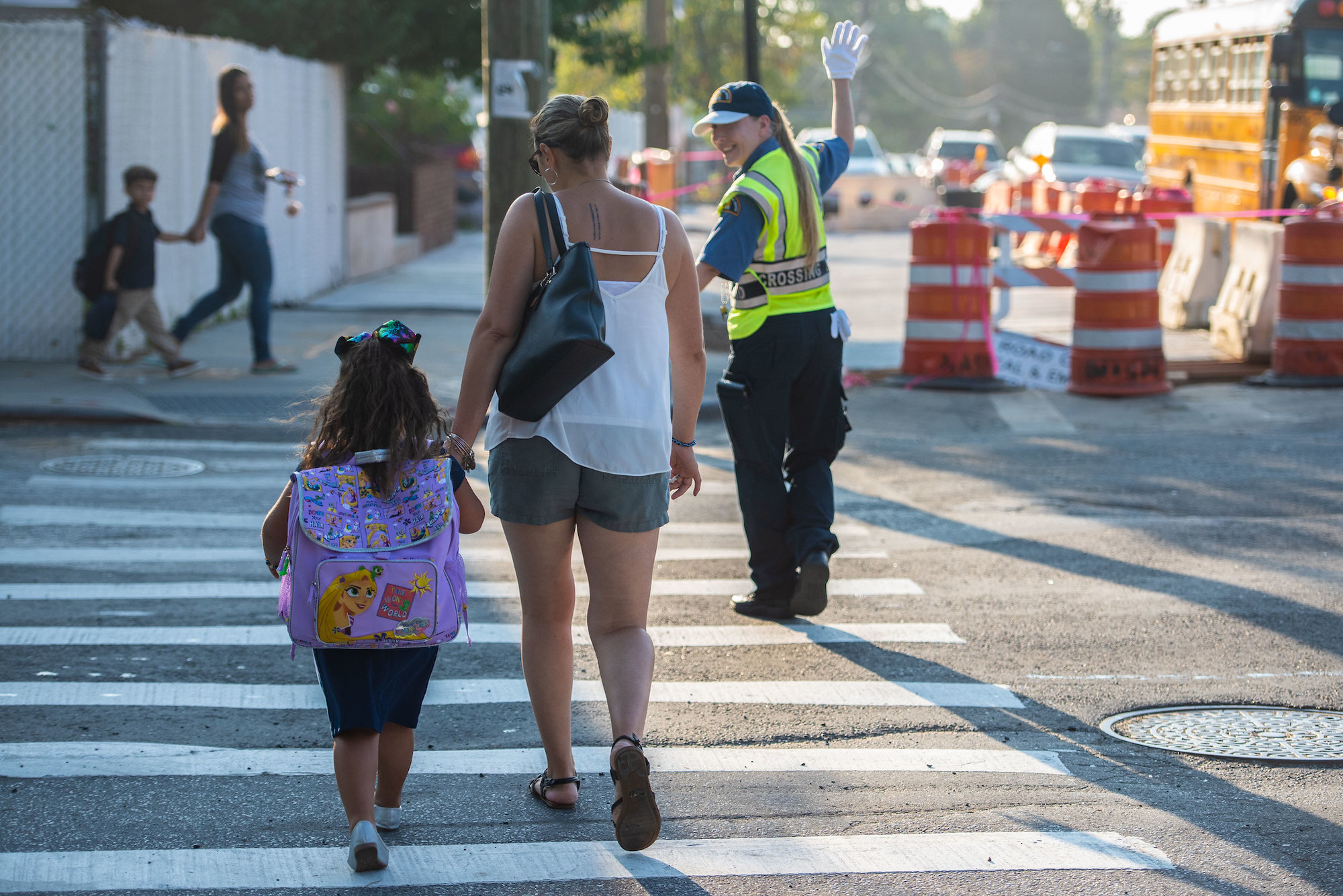 A crossing guard helps a woman and a child cross the street.