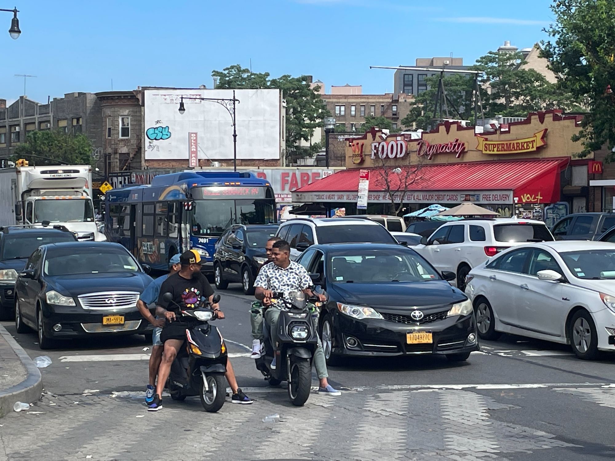 A BX12 Select Bus sits in traffic on Fordham Road.