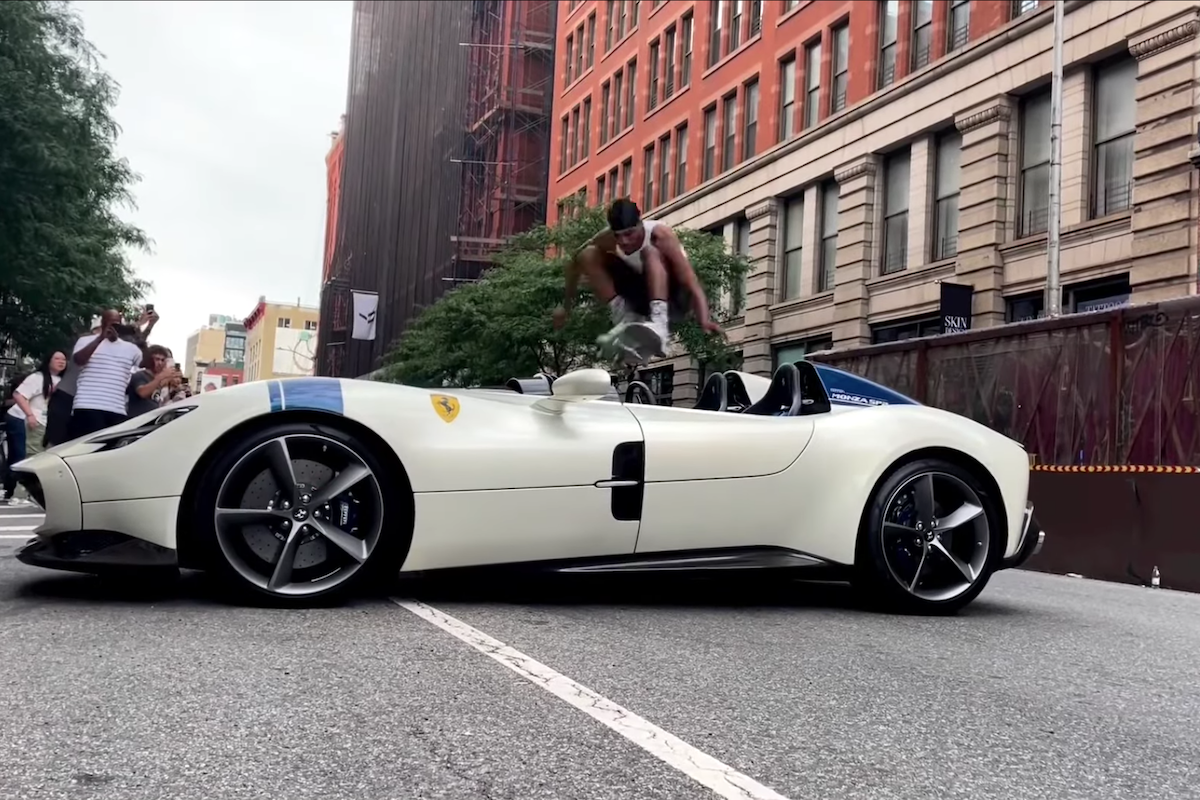 A skateboarder jumping over a white sports car on a Manhattan street.
