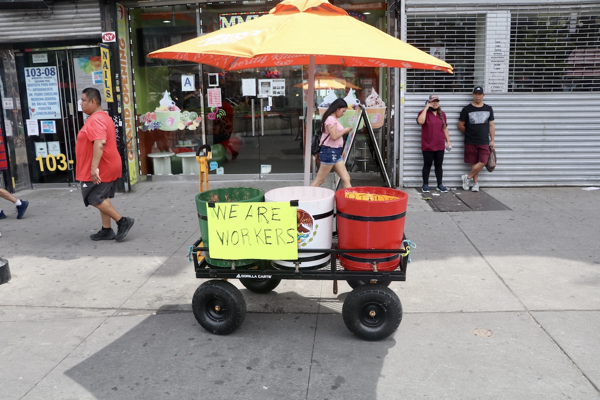 A vendor cart with a sign that says "We are workers" at Corona Plaza.