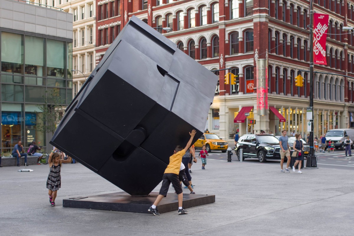 Kids push the Alamo, also known as the Astor Place Cube.