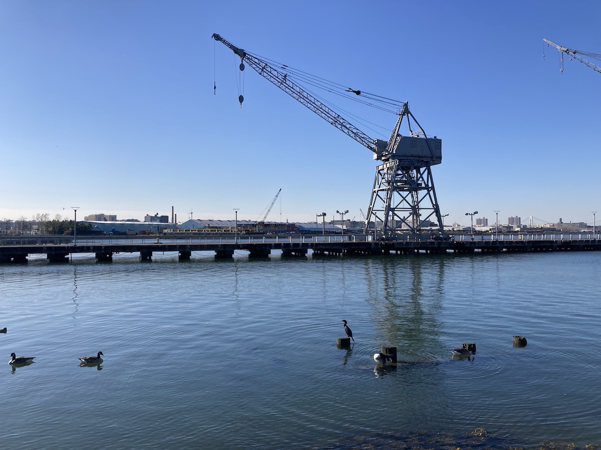 A bird sits near an industrial crane in NYC's industrial waterfront.