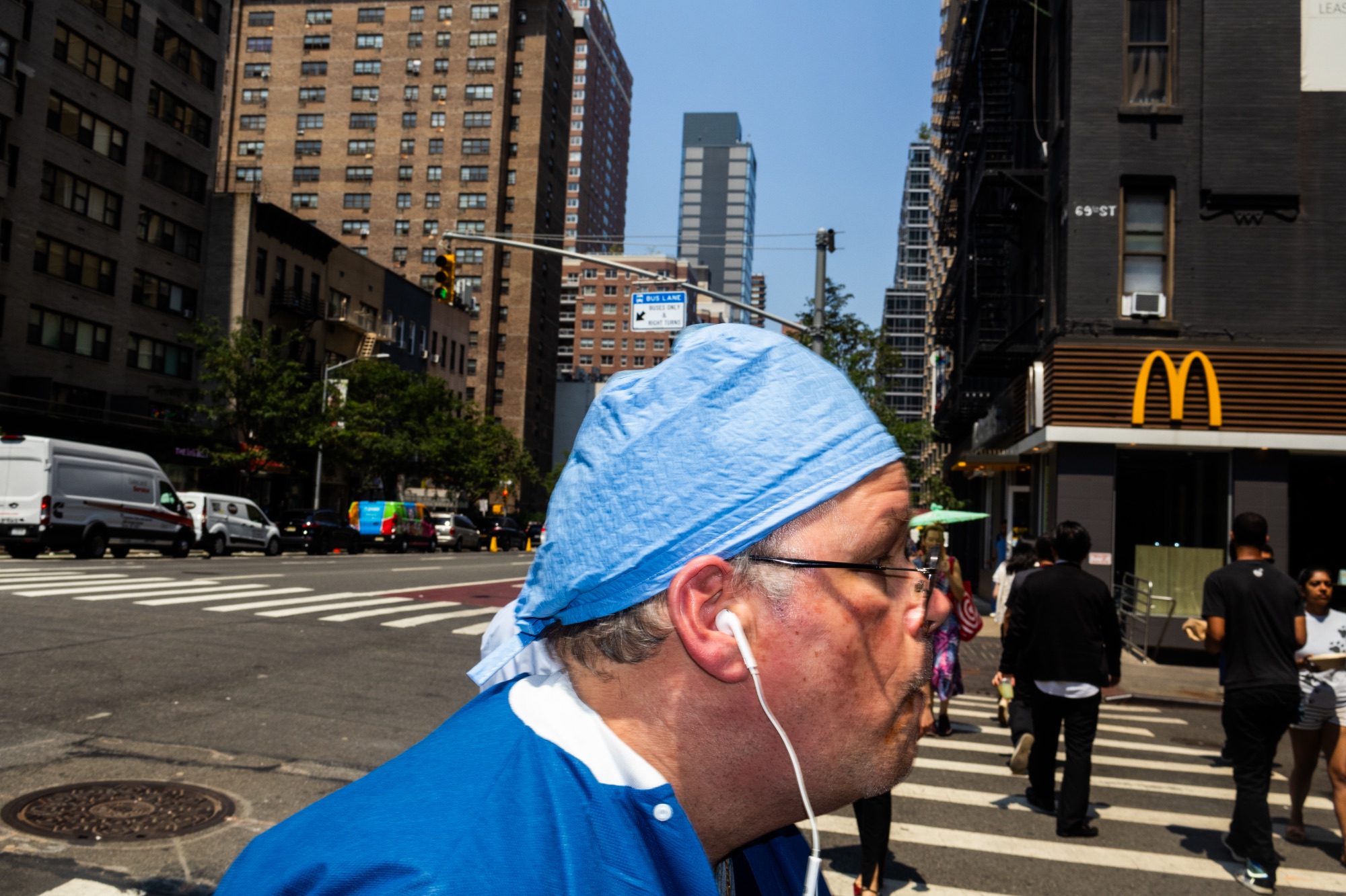 A medical worker with earbuds walks on 69th Street in the Grief Corridor.