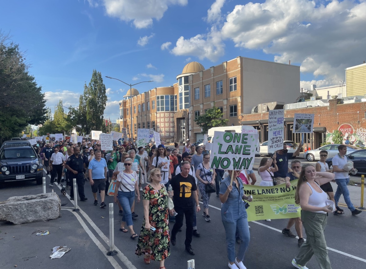 Protesters holding signs march down McGuinness Boulevard.