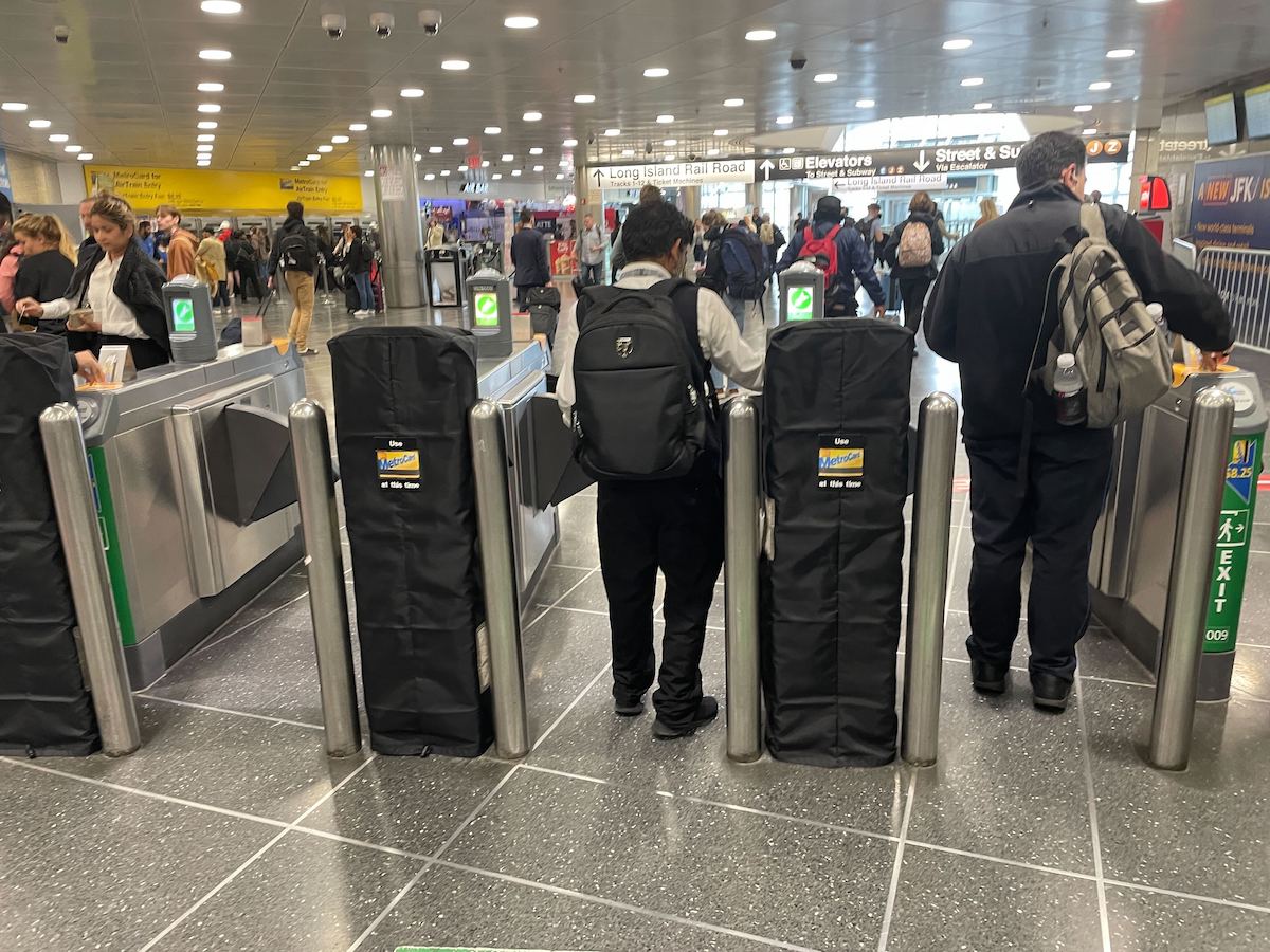 OMNY readers covered in black shrouds in front of fare gates at the JFK AirTrain exit at Jamaica.