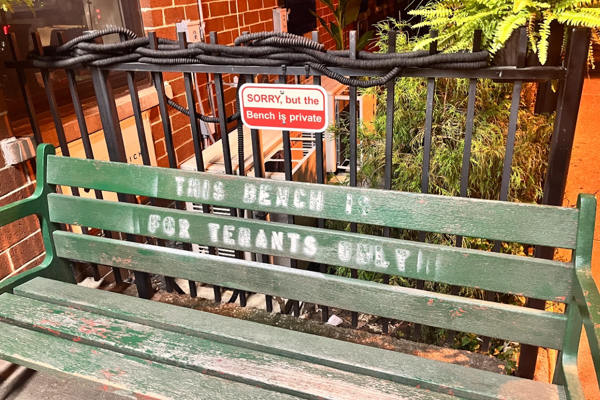 A sign that reads "Sorry but the bench is private" above a green bench with "this bench is for tenants only" spraypainted on it.