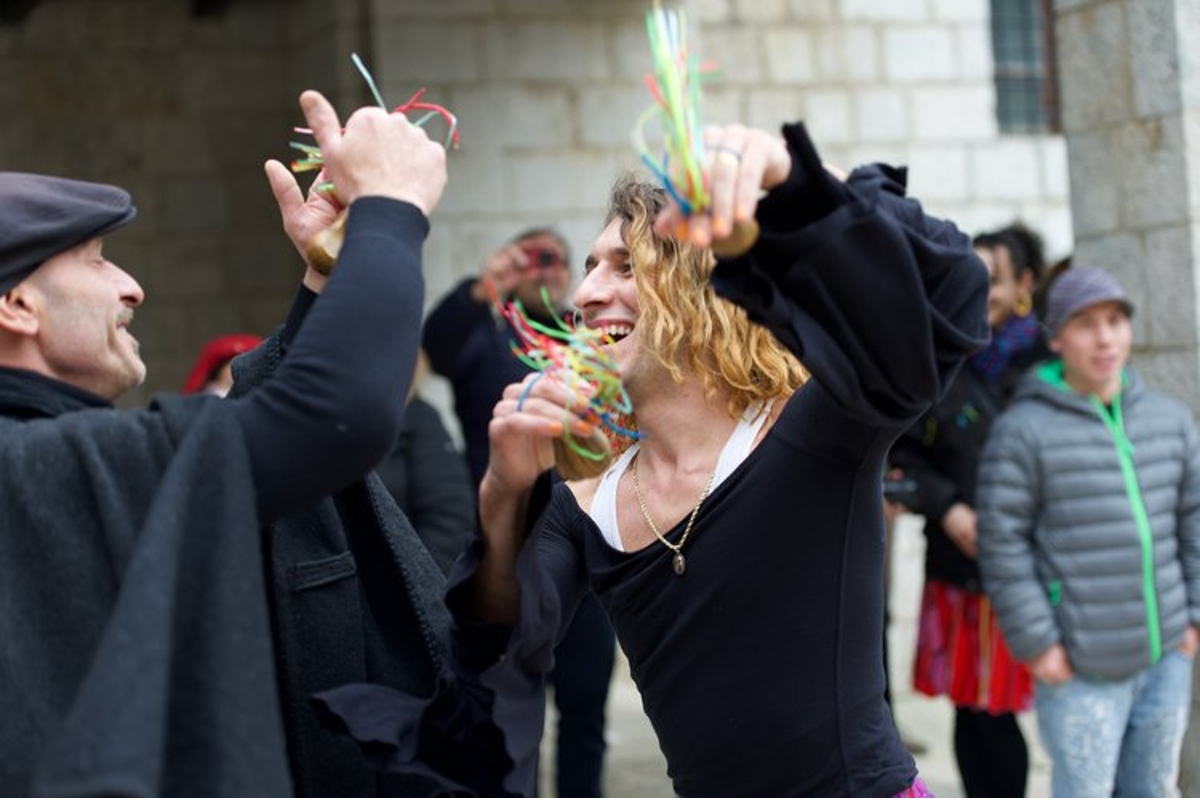 A smiling woman in a black dress dances with another person in black, on a street in Italy.