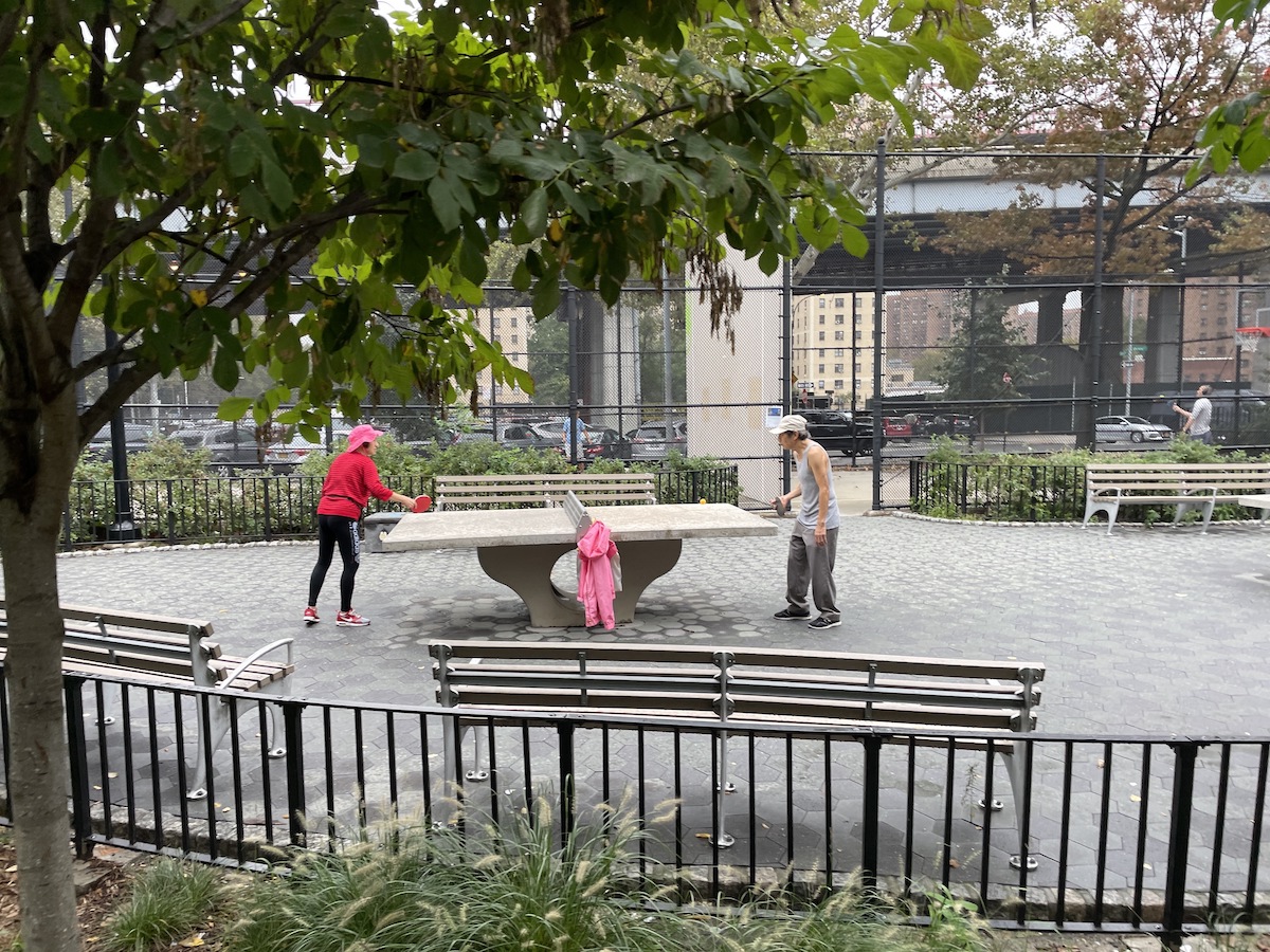 Two people play ping pong in the park.