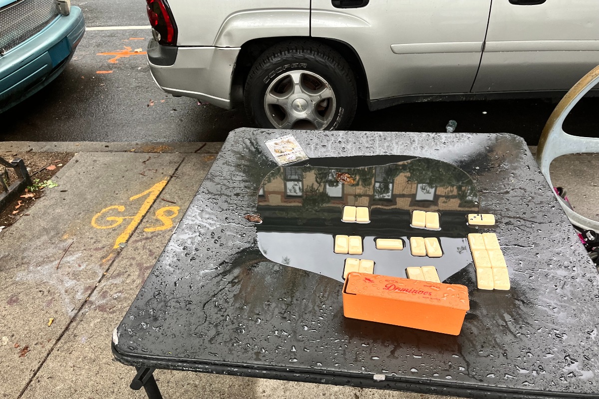 A puddle of rainwater on a black table used to play dominos