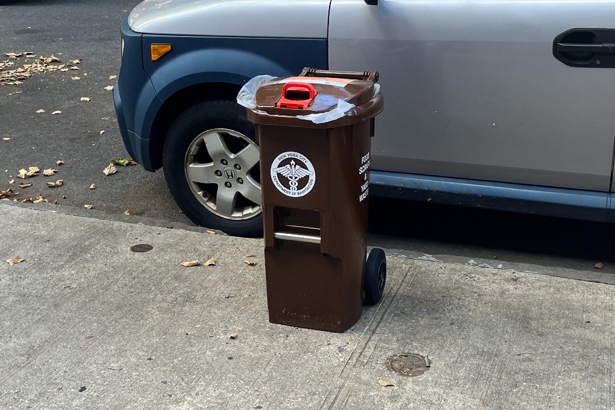 a brown compost bin on a sidewalk