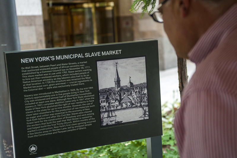 A person looks at a plaque about New York's municipal slave market.