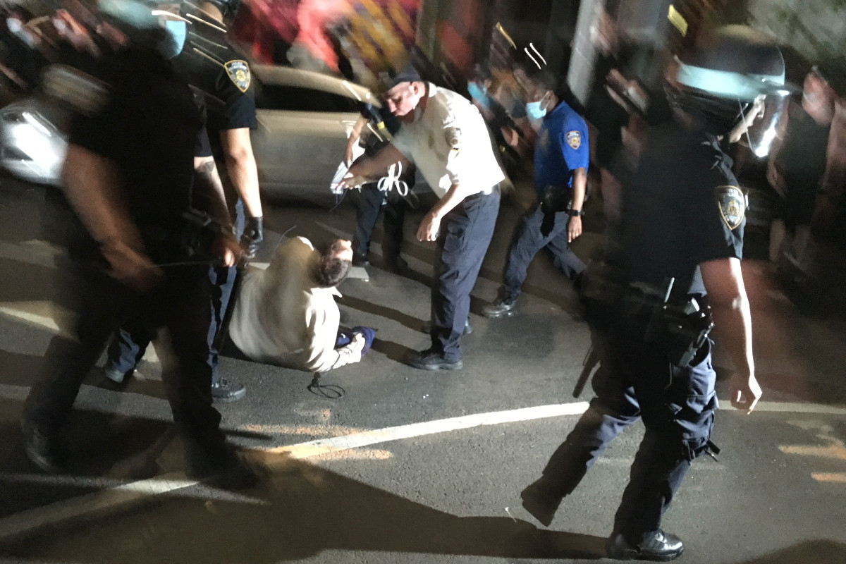 Police mill around a man on the ground during the George Floyd protests