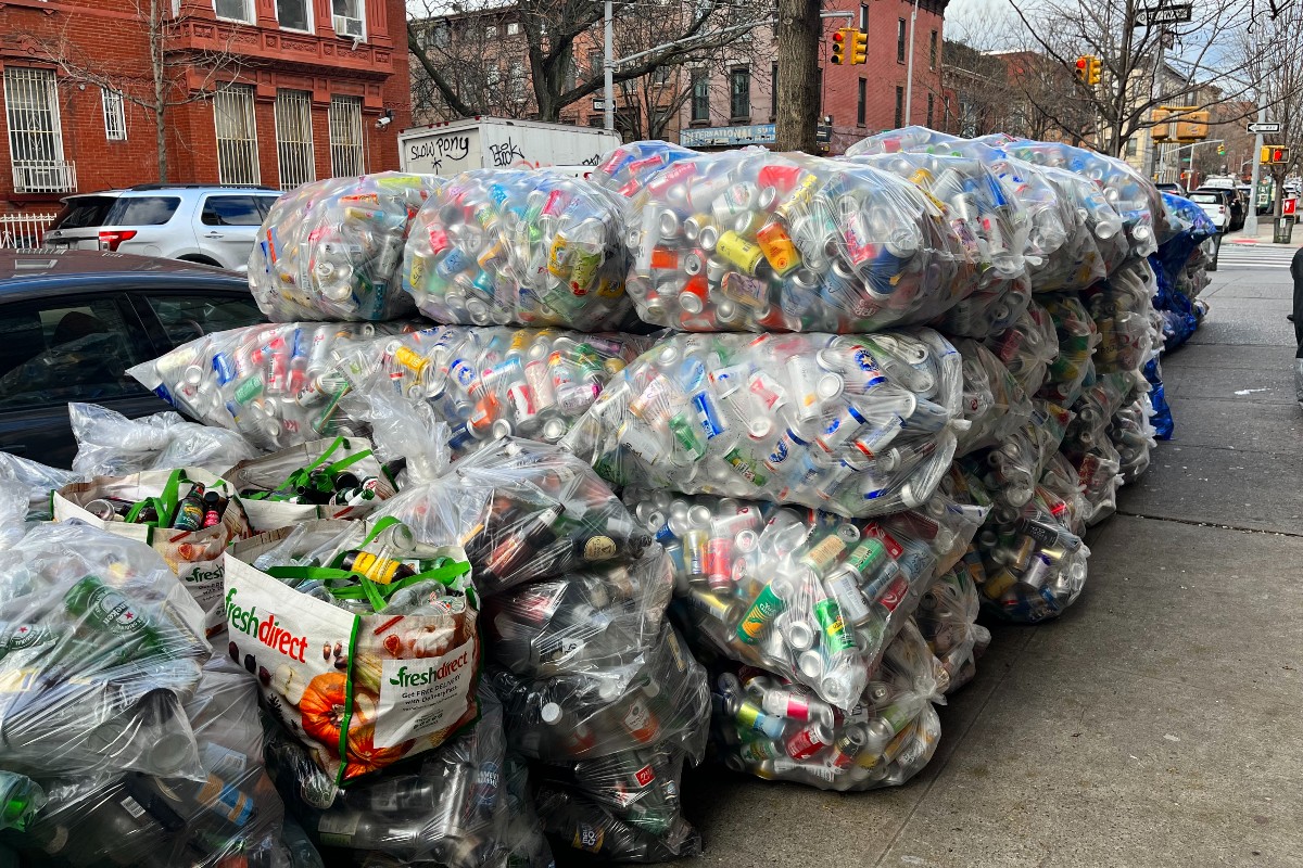 Cans in bags on the street waiting for commercial recycling pickup.
