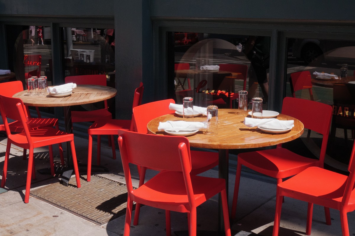 A group of red chairs sitting around a wooden table at a restaurant in New York City.